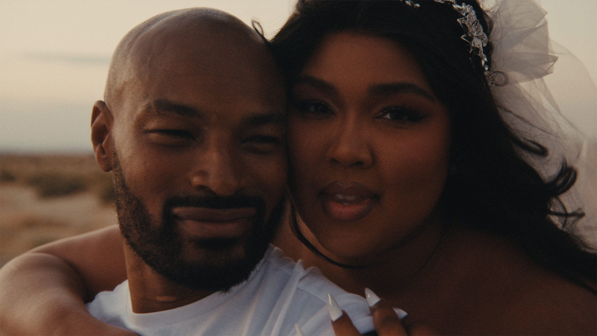 From the ‘2 Be Loved (Am I Ready)’ music video: Lizzo in a wedding gown embraces a man from behind