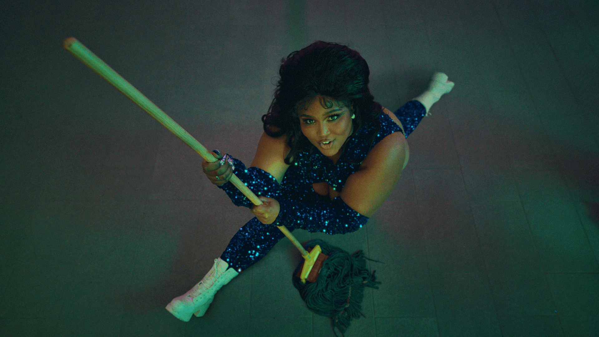 From the ‘About Damn Time’ music video: Lizzo holds a mop while doing the splits